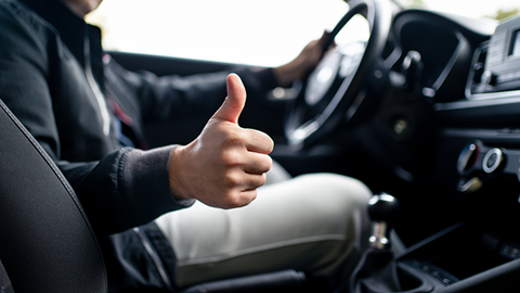 homme au volant d'une voiture levant son pouce